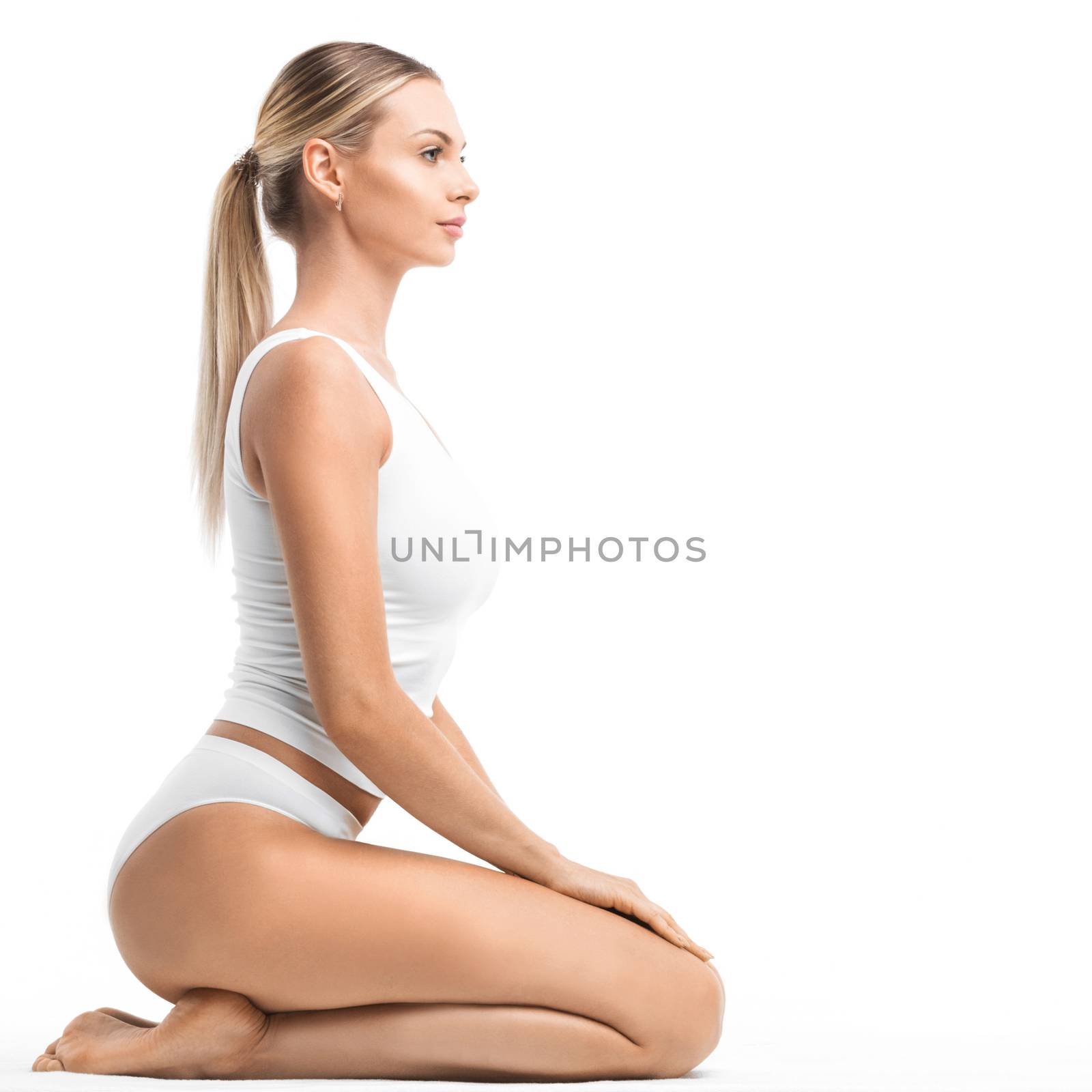 Young beautiful woman in white cotton underwear sitting on knees isolated on white background