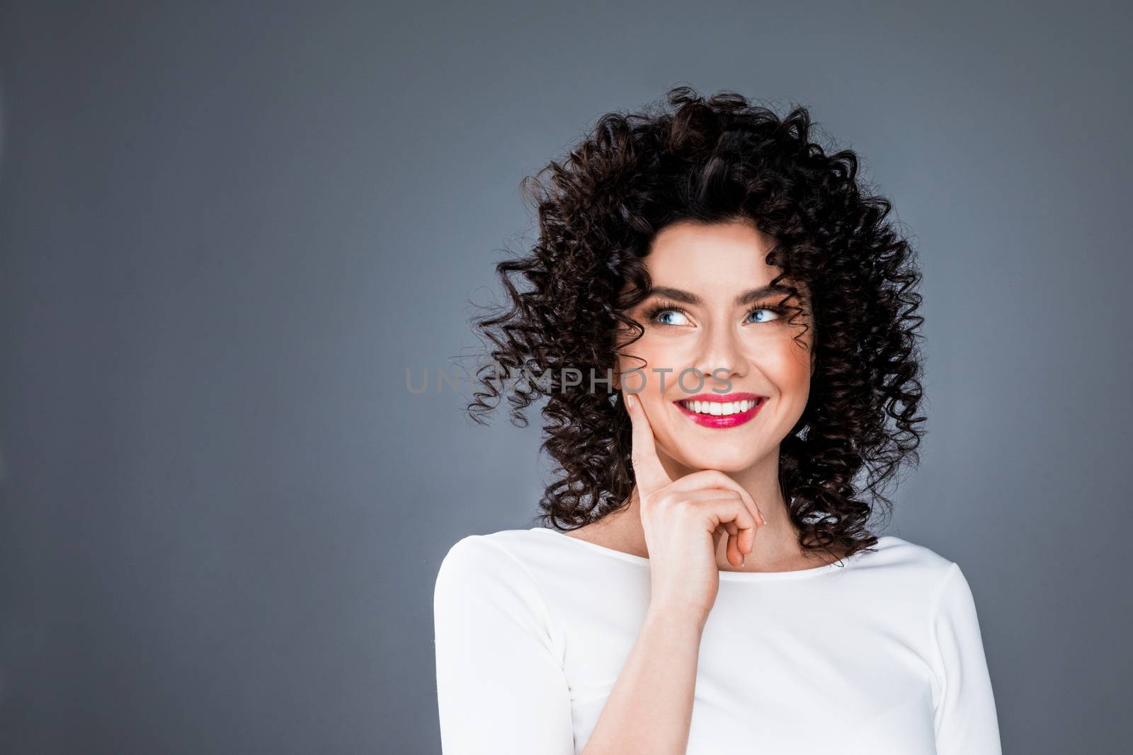 Portrait of smiling woman with finger on chin look aside thinking about something, making a choice