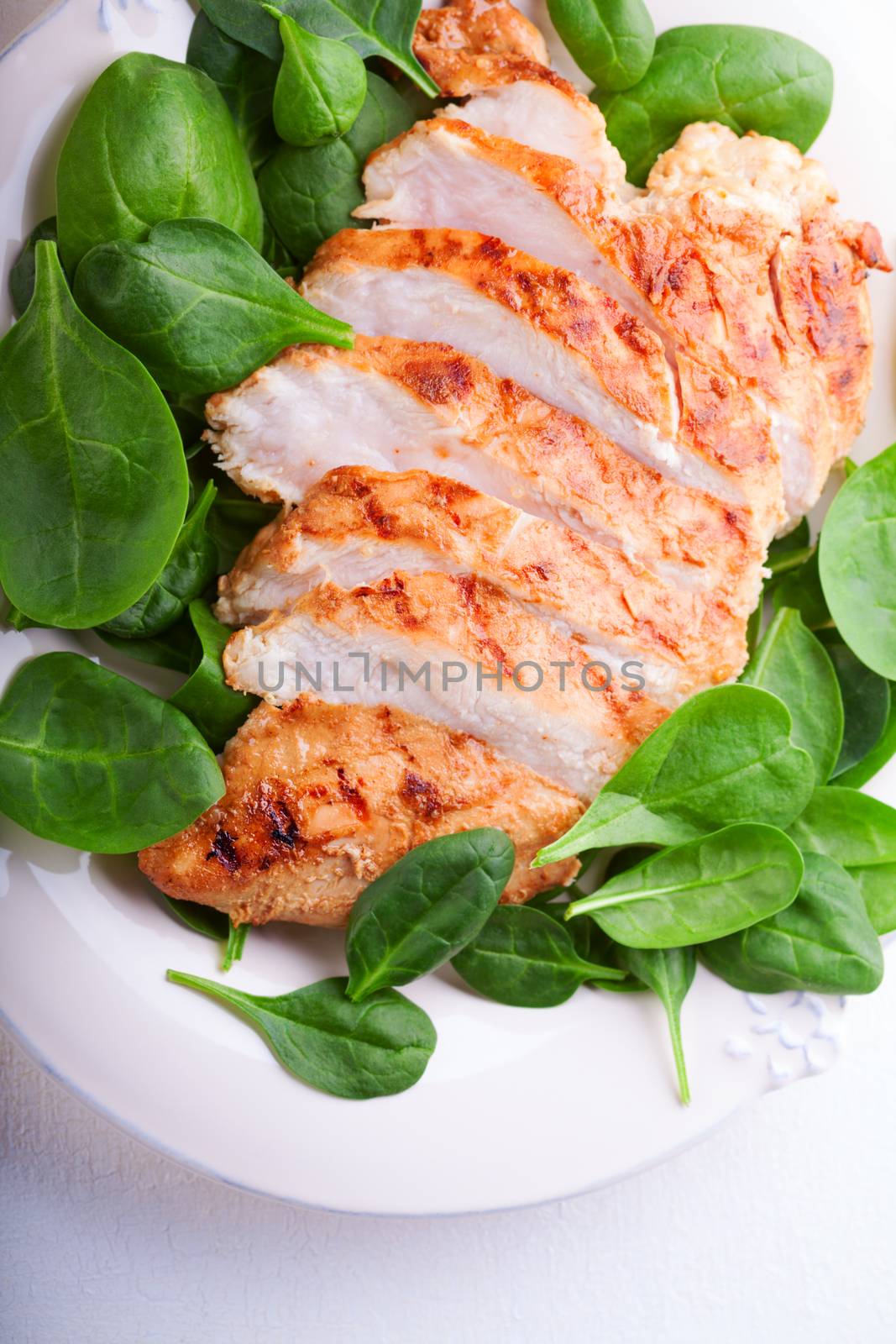 Grilled chicken breast with salad served on a white plate