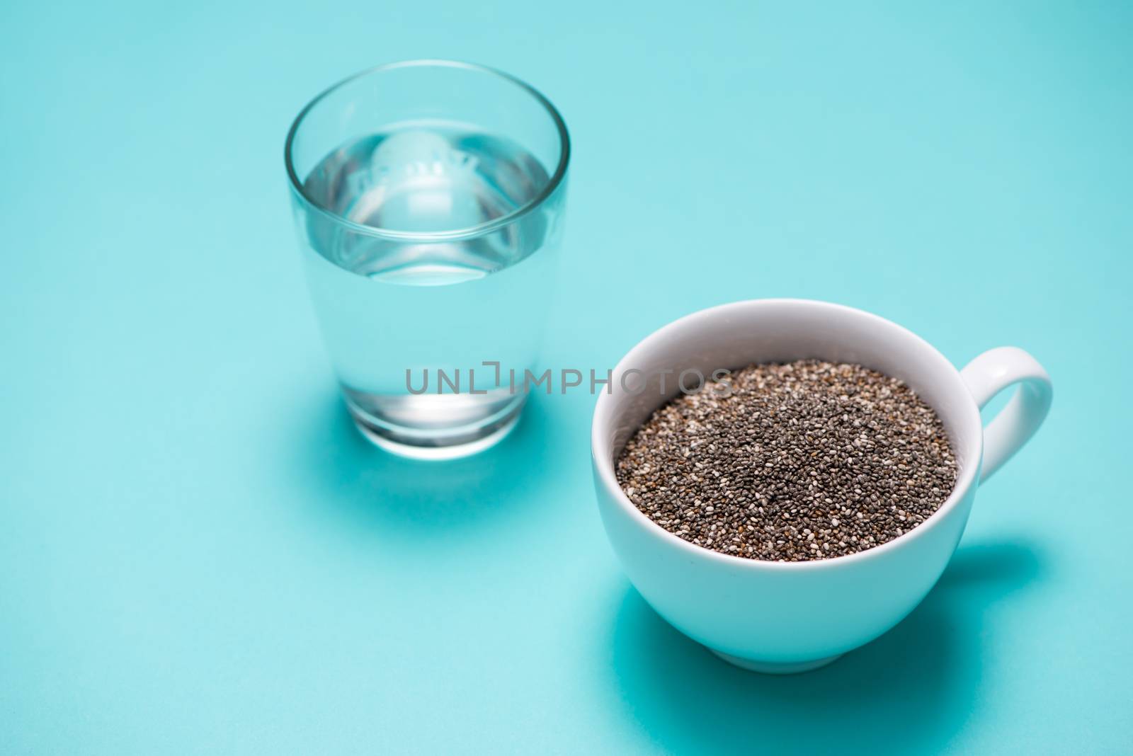 Glass of water and healthy chia seeds in a cup. Text space.