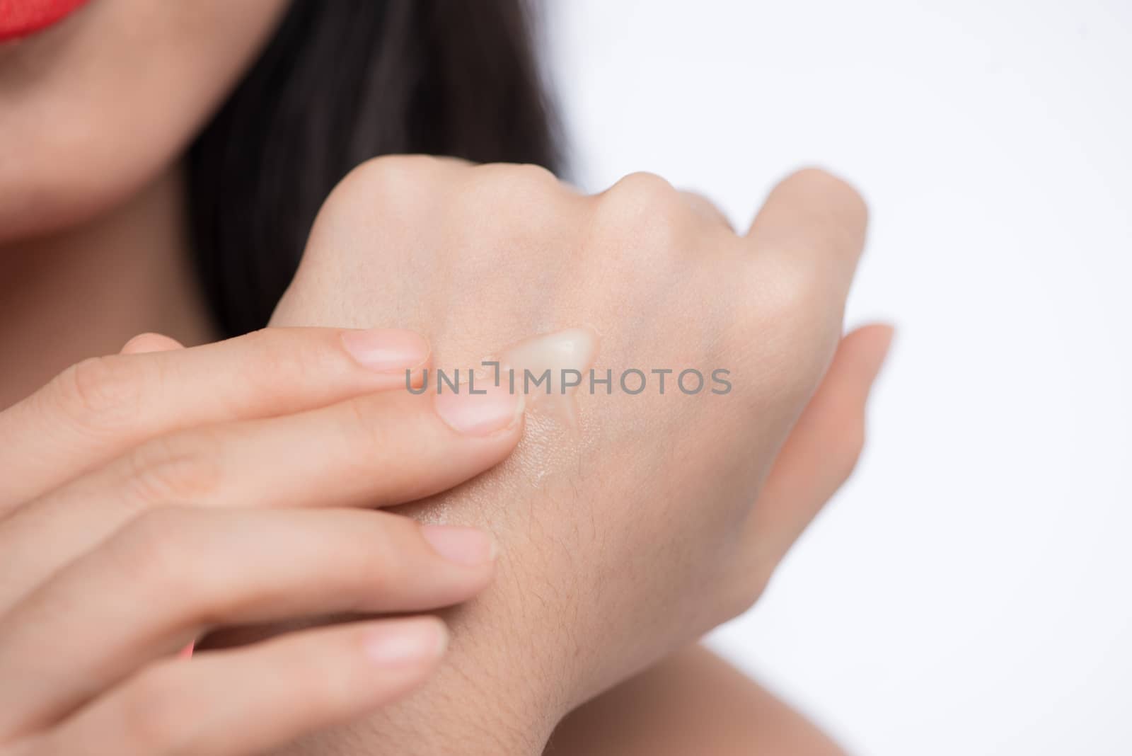 Pretty asian young woman applying cream on her hand