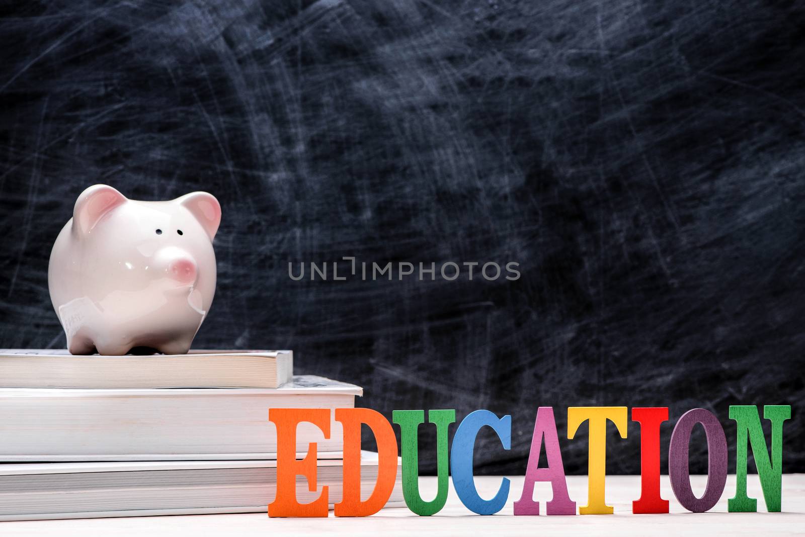 Education financial saving. Pink Piggy bank on top of books with chalkboard.