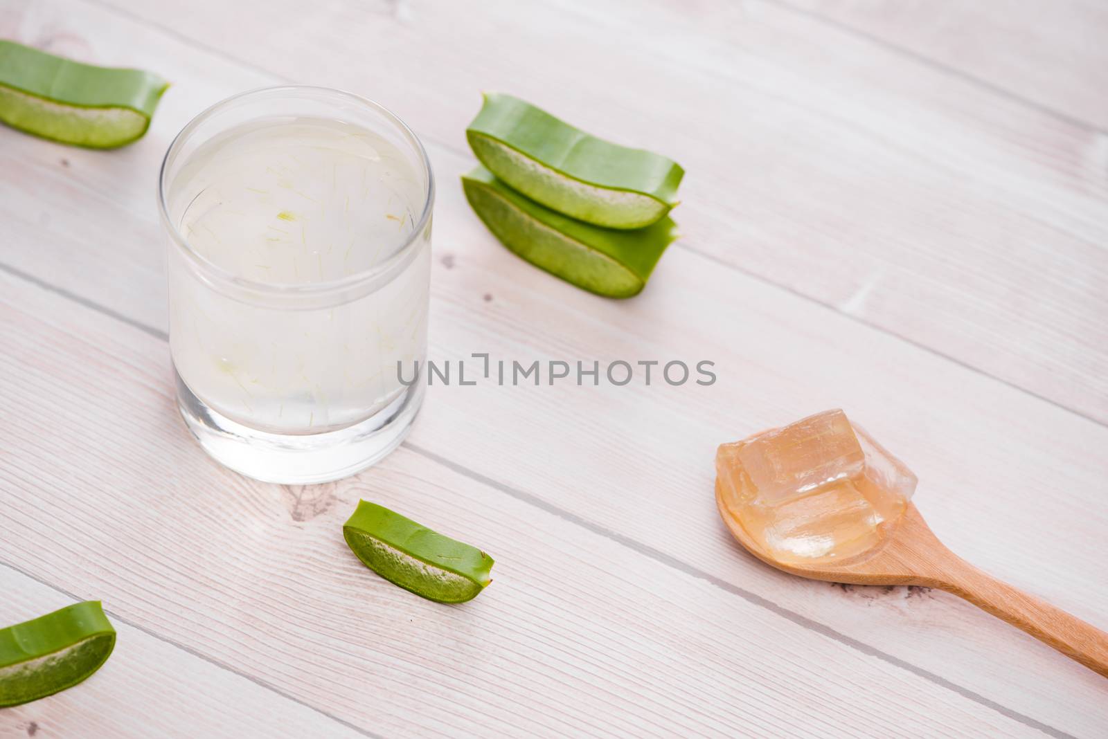 Glass of aloe vera juice with slices on a wooden table