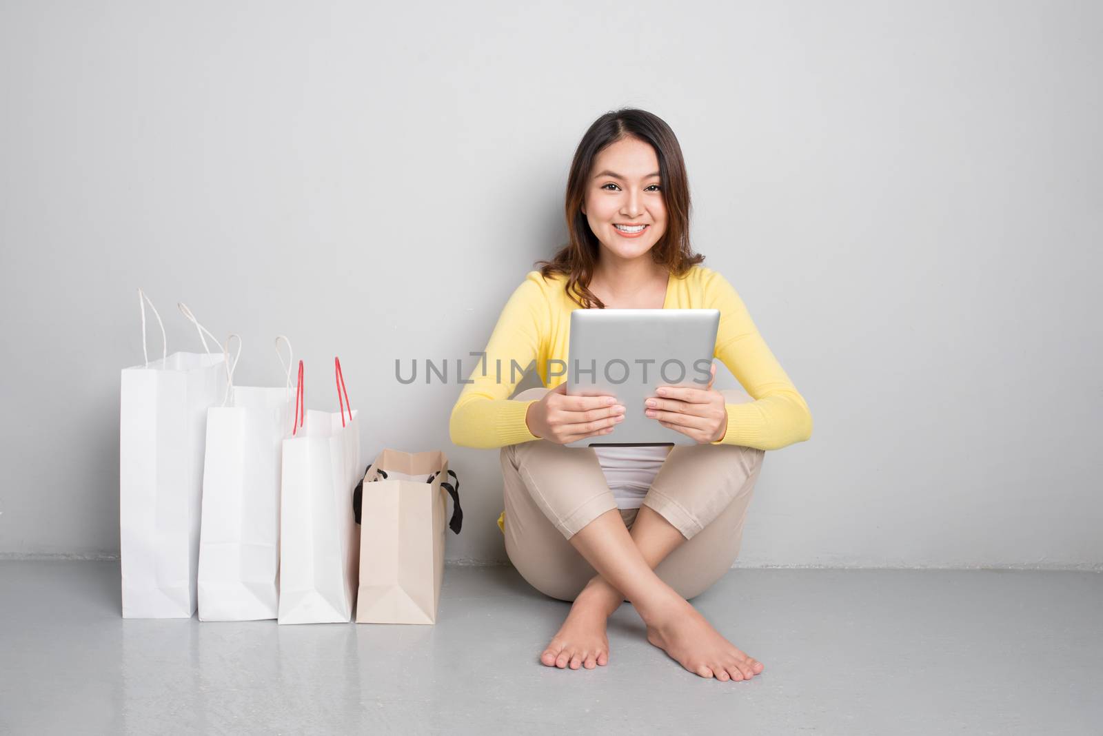 Young asian woman shopping online at home sitting besides row of by makidotvn