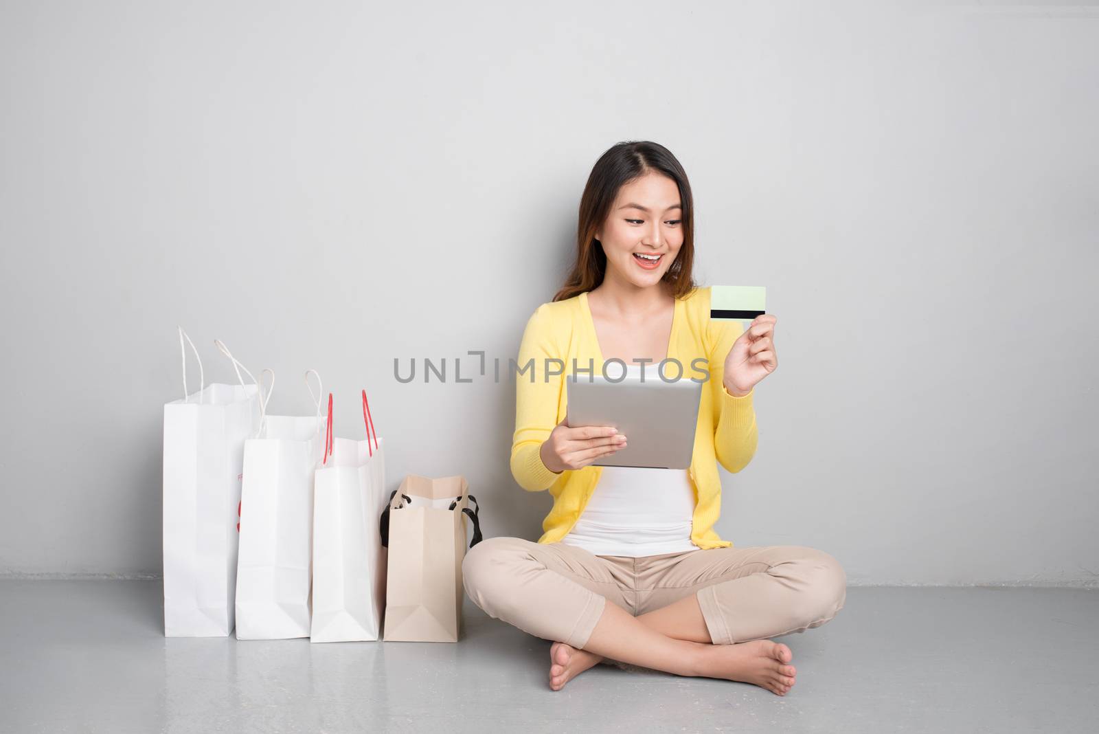 Young asian woman shopping online at home sitting besides row of shopping bags