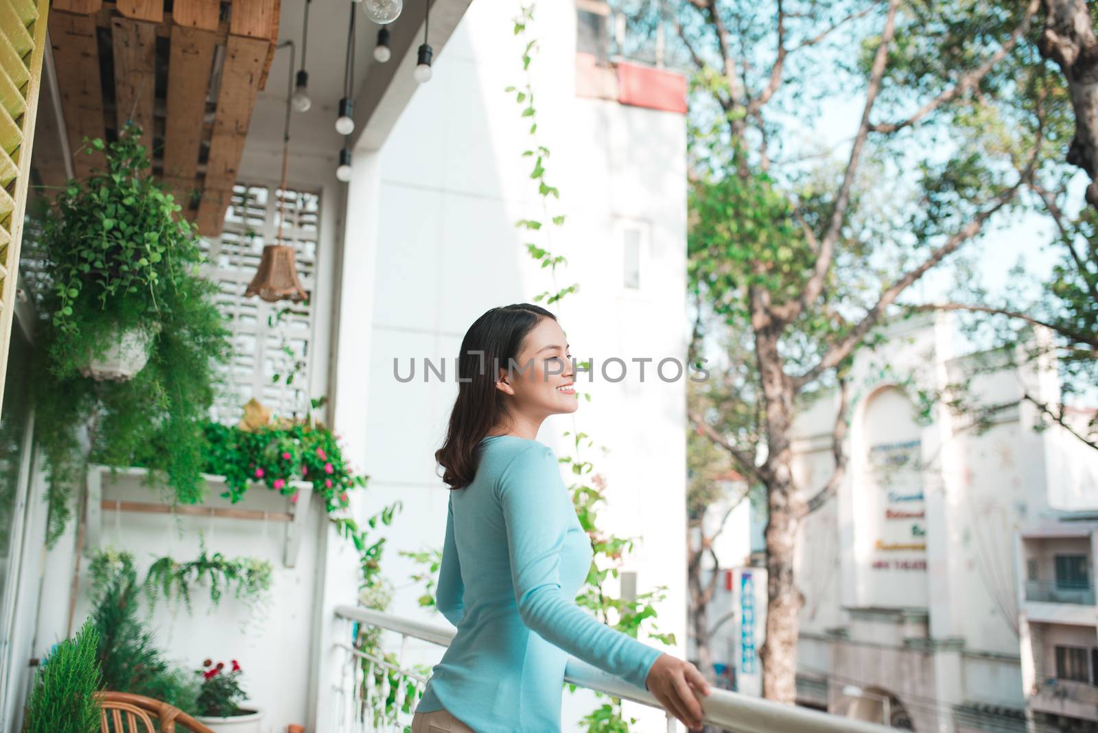 Beautiful asian girl enjoying the freshness on balcony by makidotvn
