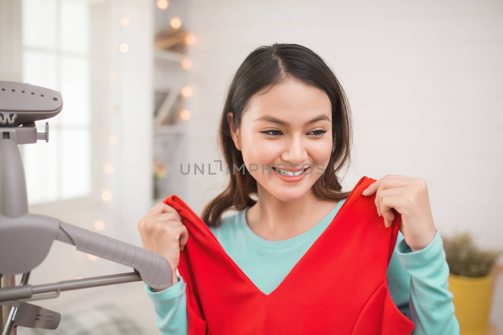 A lovely asian girl trying on new dress at home.