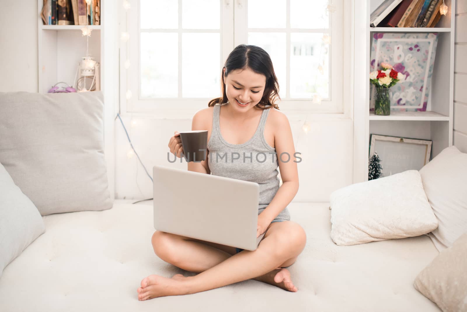 Happy casual beautiful asian young woman working on a laptop at  by makidotvn