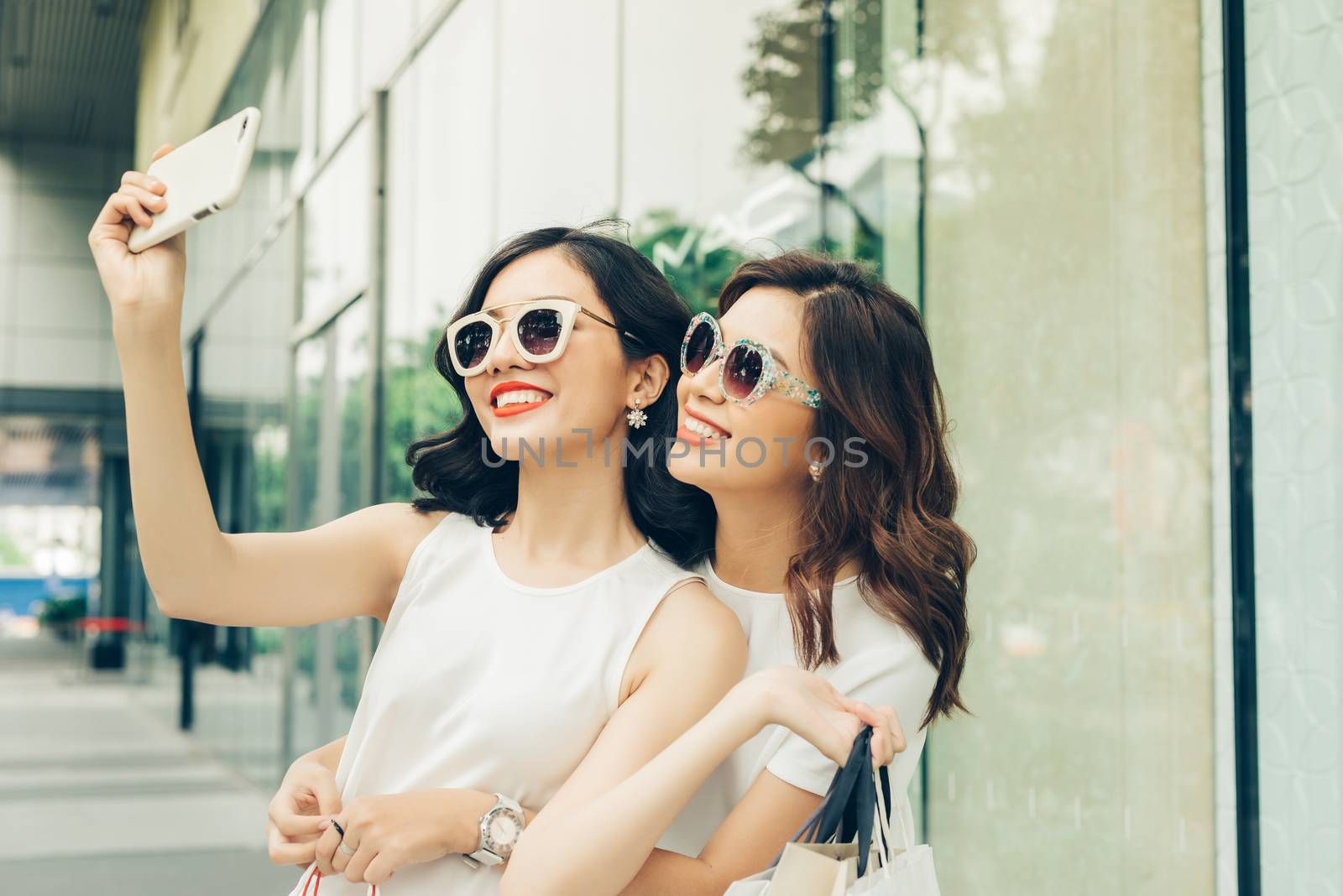Beautiful asian girls with shopping bags taking selfie photo at  by makidotvn