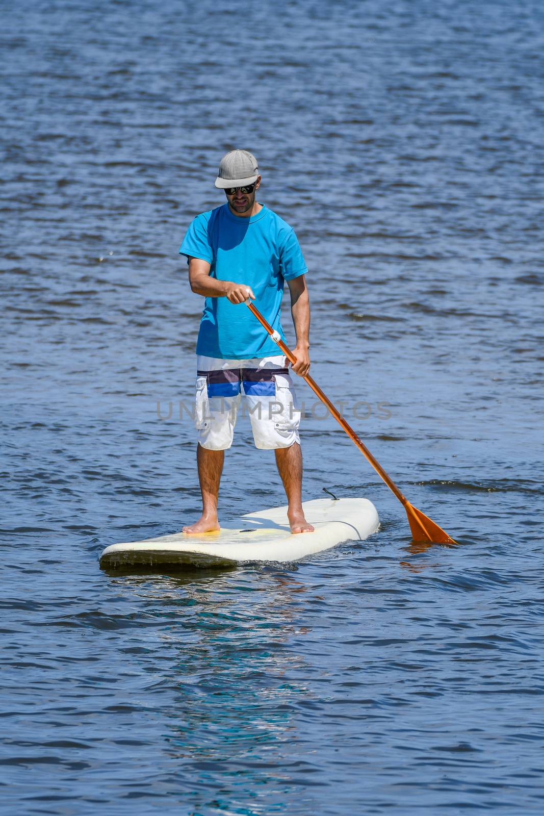 Man stand up paddleboarding by homydesign