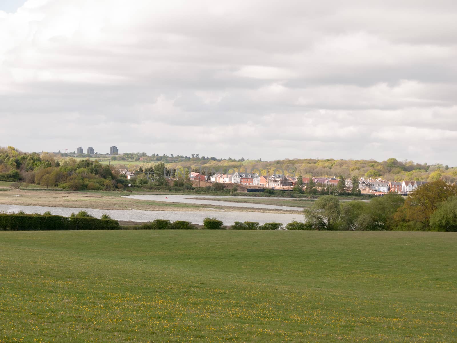 a coastal town in the distance behind a big field of grass