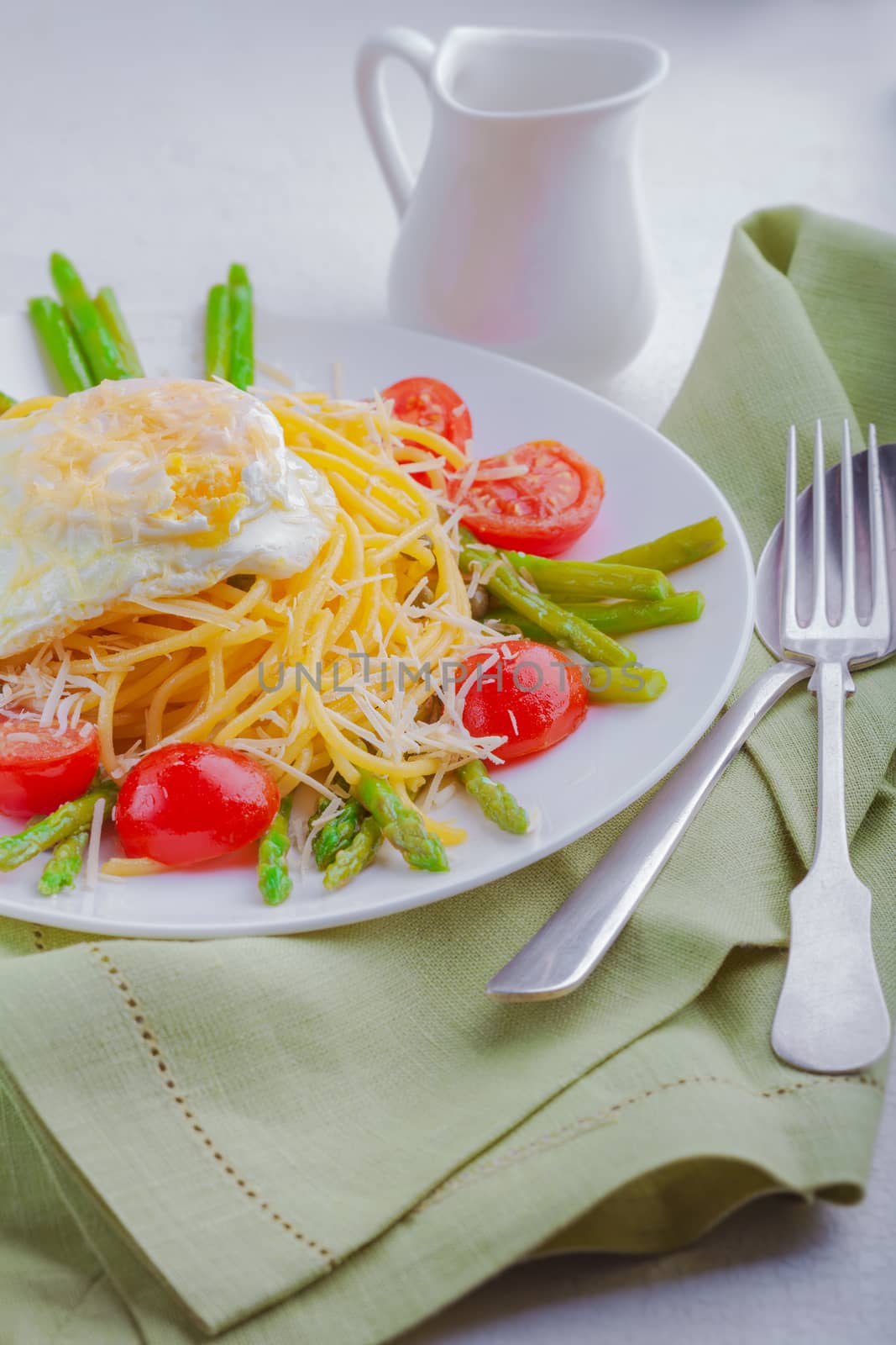 Spaghetti with egg and vegetables on a white plate