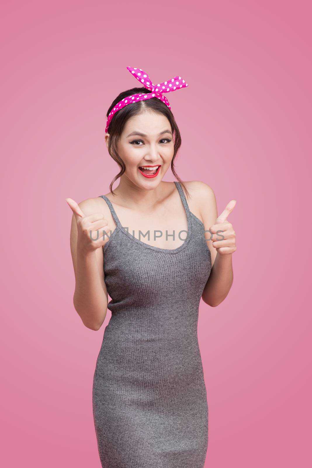 Portrait of asian girl with pretty smile in pinup style with hands gesture on pink background