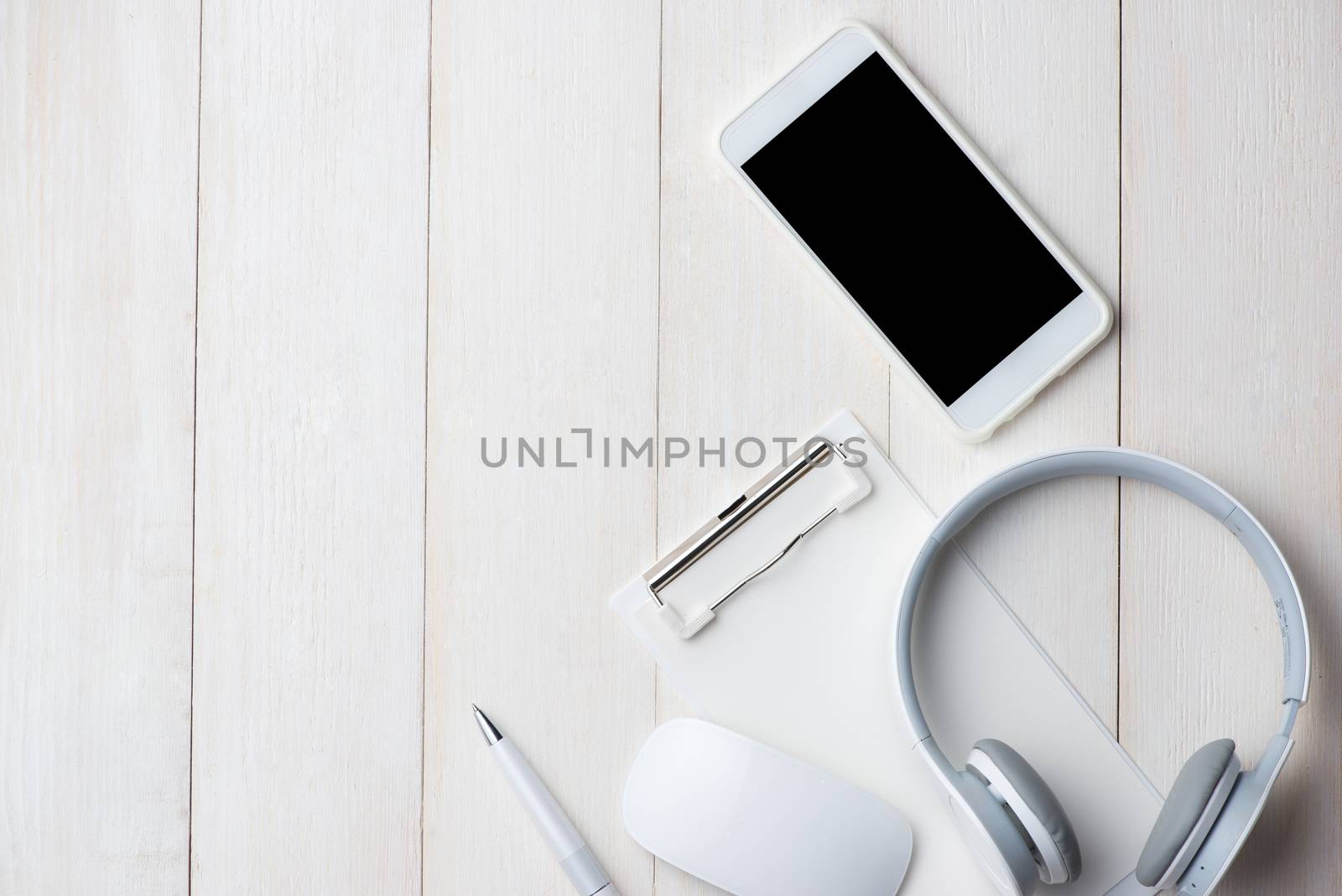 Notebook and smartphone on white table with headphone. View from above