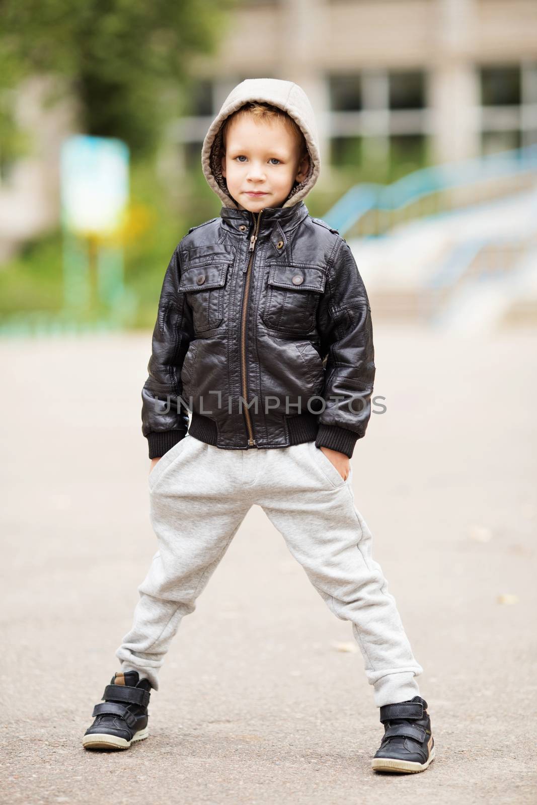 Full-length portrait of adorable little urban boy wearing black leather jacket. City style. Urban kids.