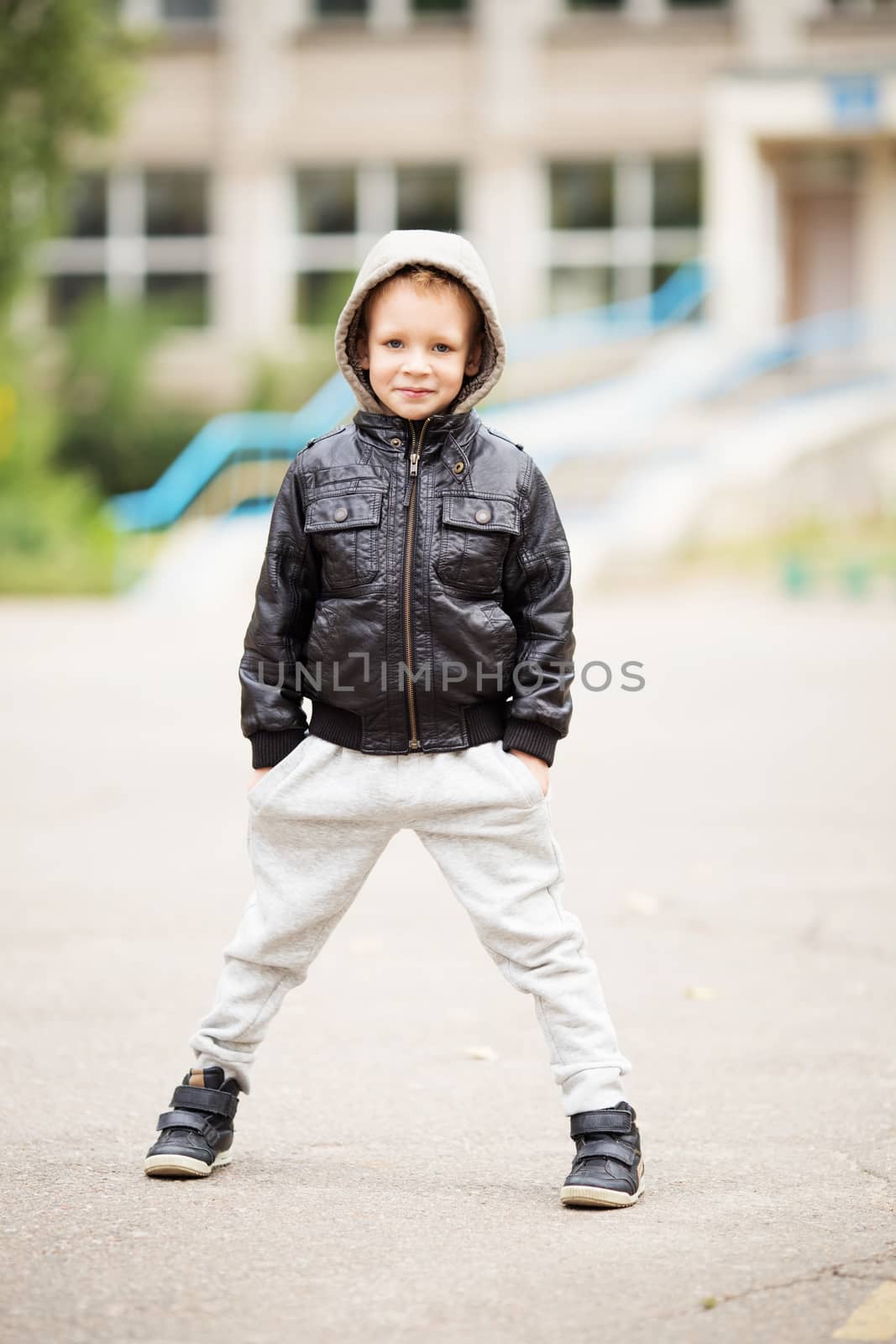 Full-length portrait of adorable little urban boy wearing black leather jacket. City style. Urban kids.