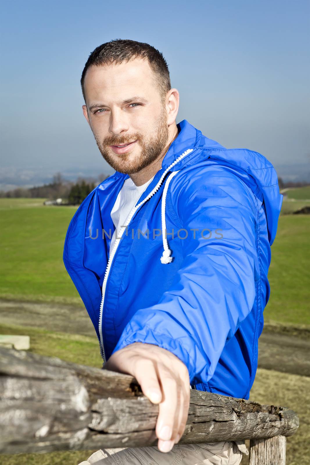 An image of a handsome man with a beard in a blue outdoor clothing