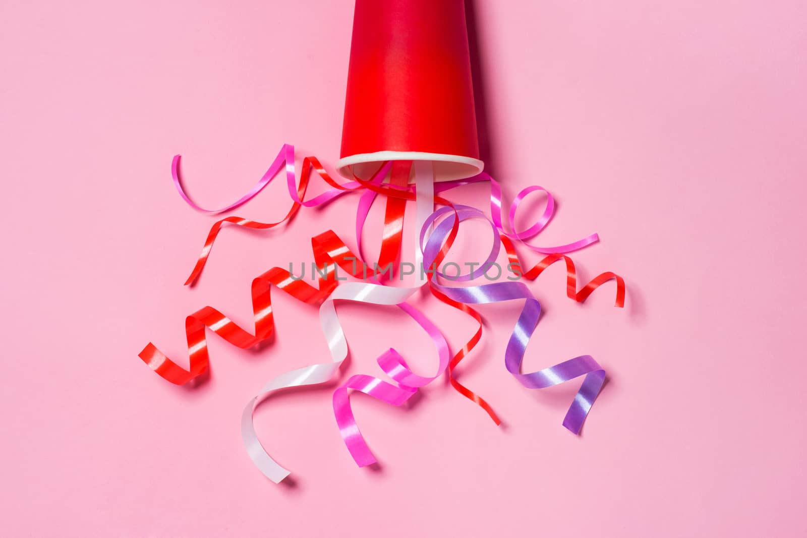Flat lay of Celebration. Paper cup with colorful party streamers by makidotvn