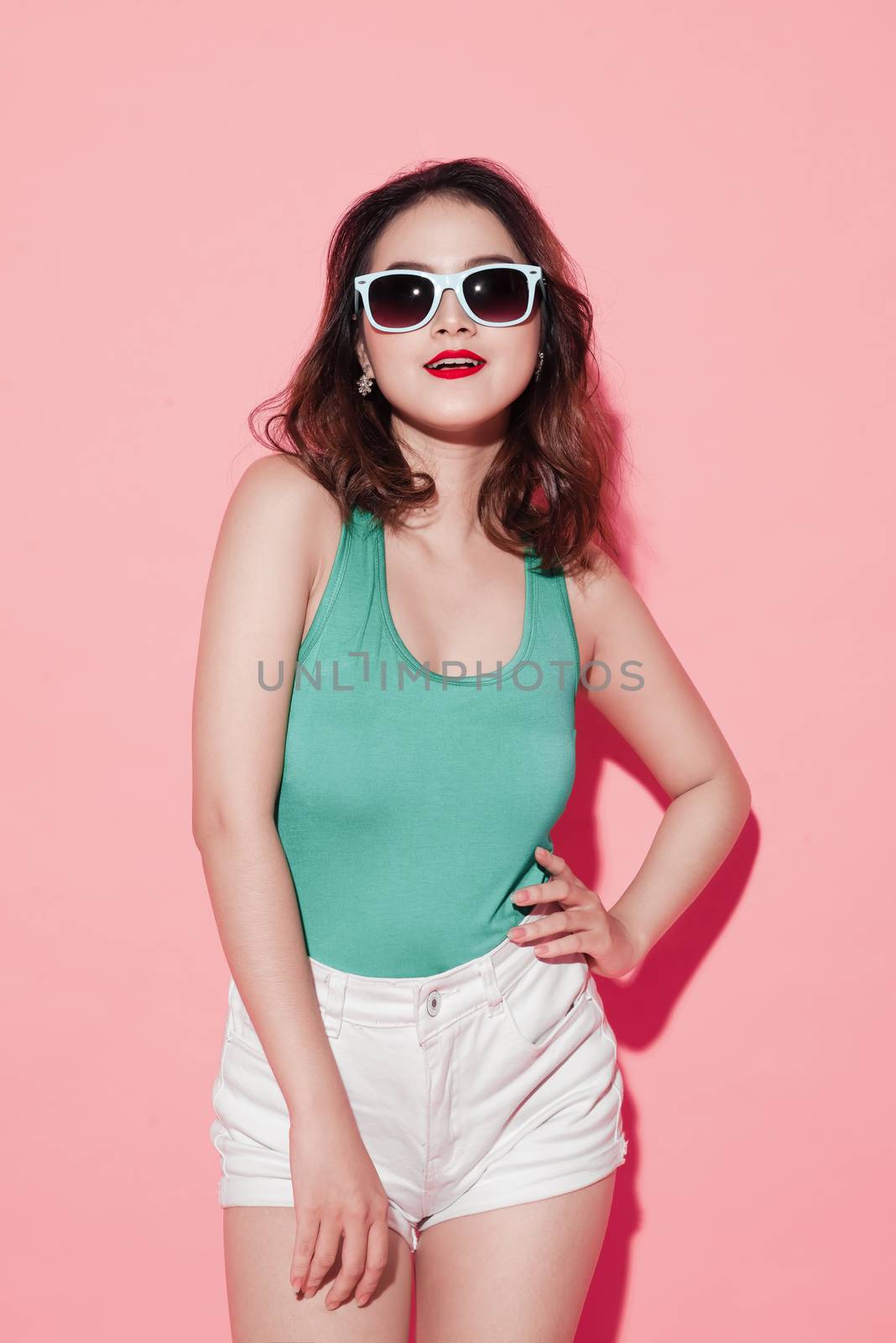 Summer asian young woman with professional makeup and stylish hairstyle on pink background.