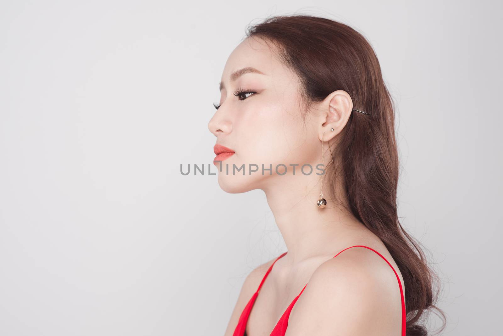 Portrait of stylish asian woman wearing red dress on grey backgr by makidotvn