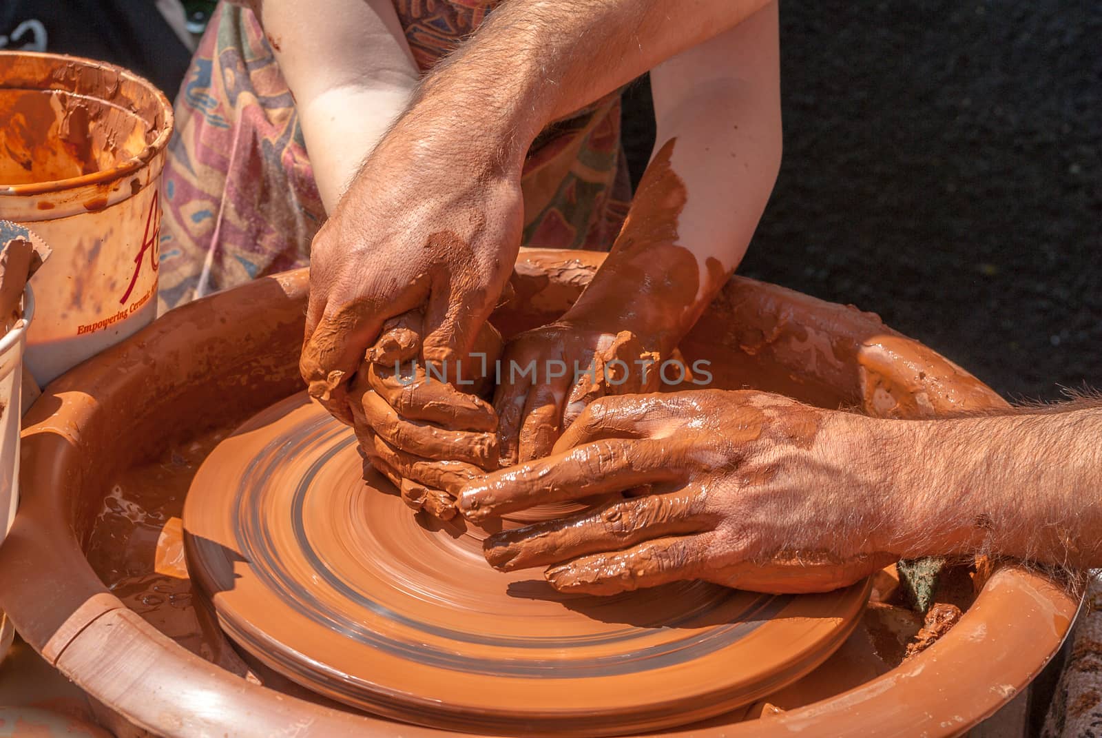the teacher teaches to sculpt in clay pot on a turning pottery wheel
