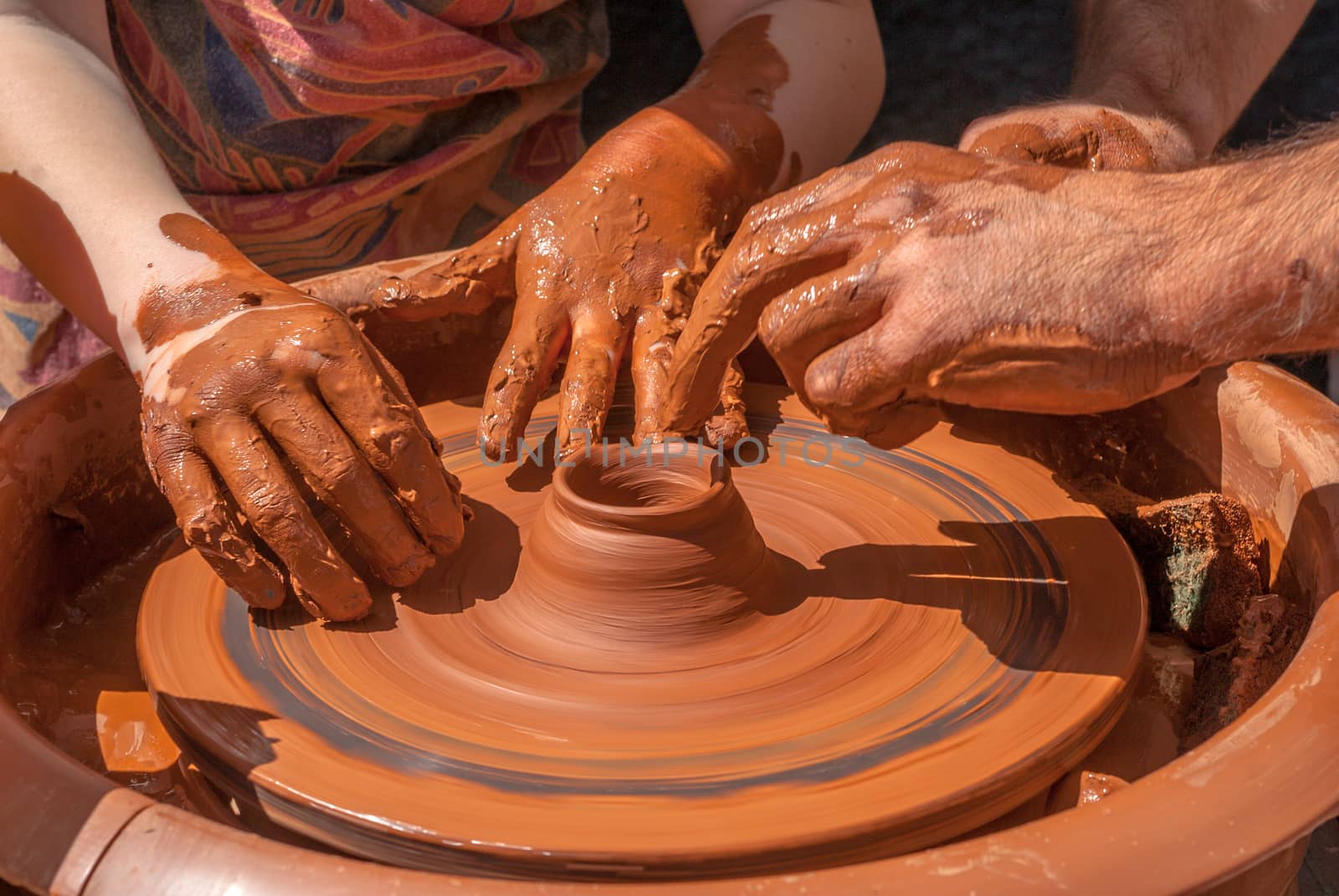 potter teaches to sculpt in clay pot on a turning pottery wheel