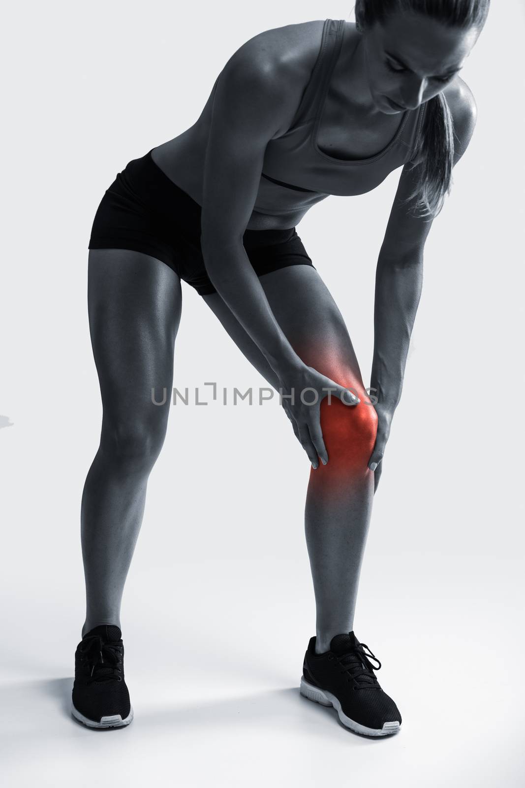 Studio shot of a sporty young woman holding her knee in pain