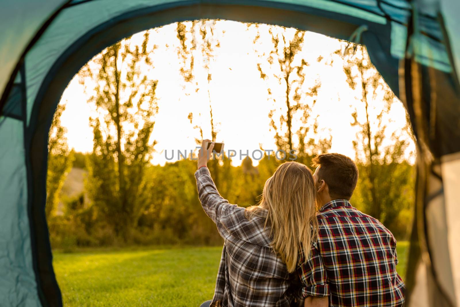 Shot of a happy couple camping on the nature and making a selfie