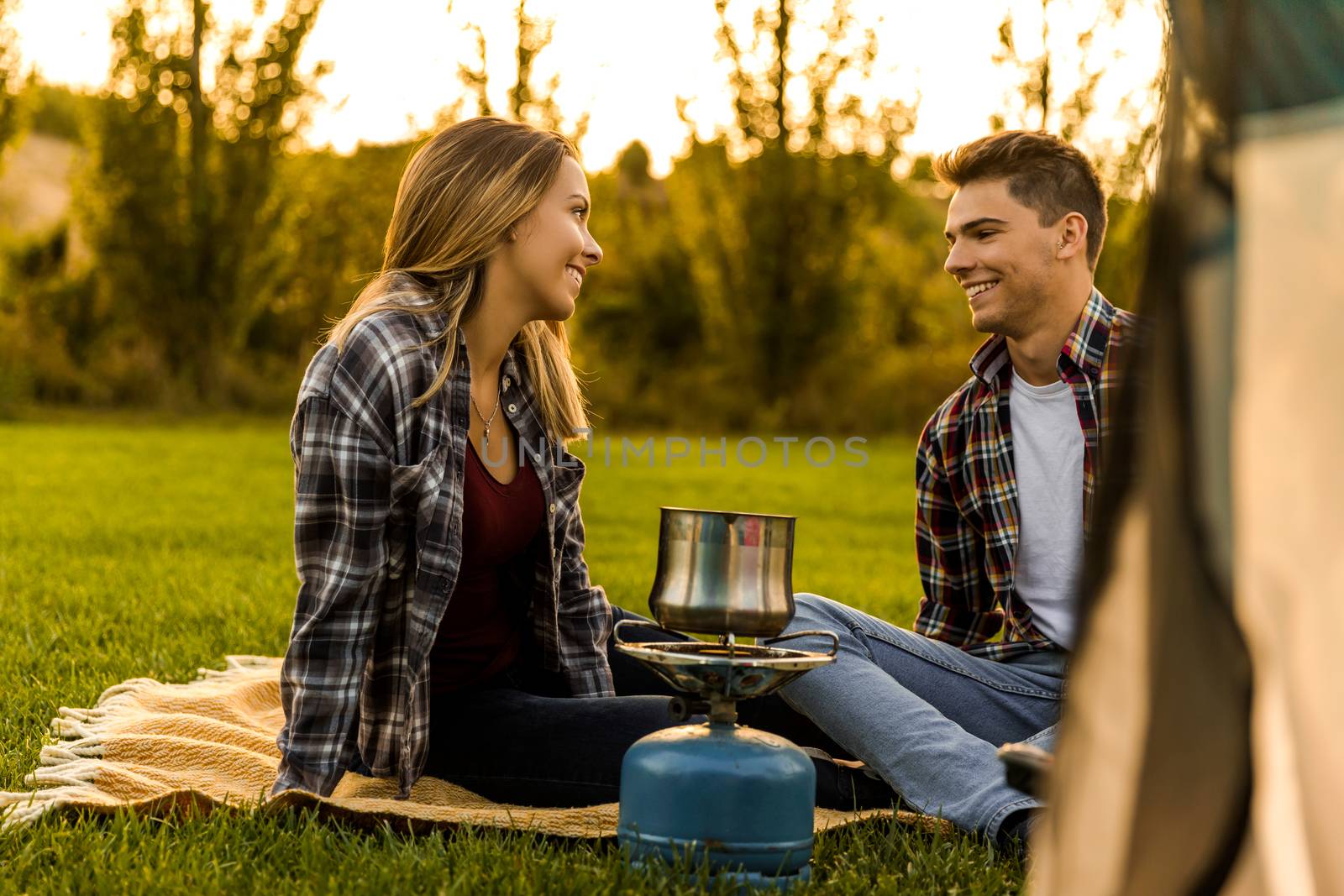 Shot of a happy couple camping on the nature and cooking