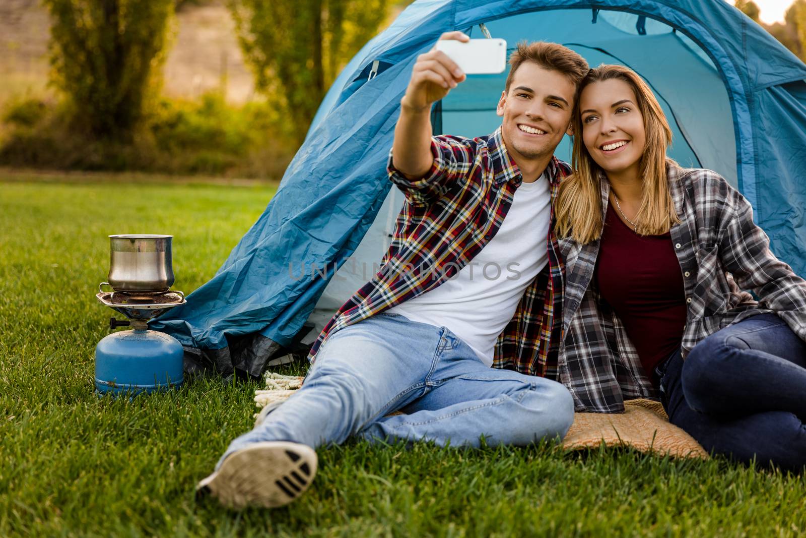 Shot of a happy couple camping on the nature and making a selfie