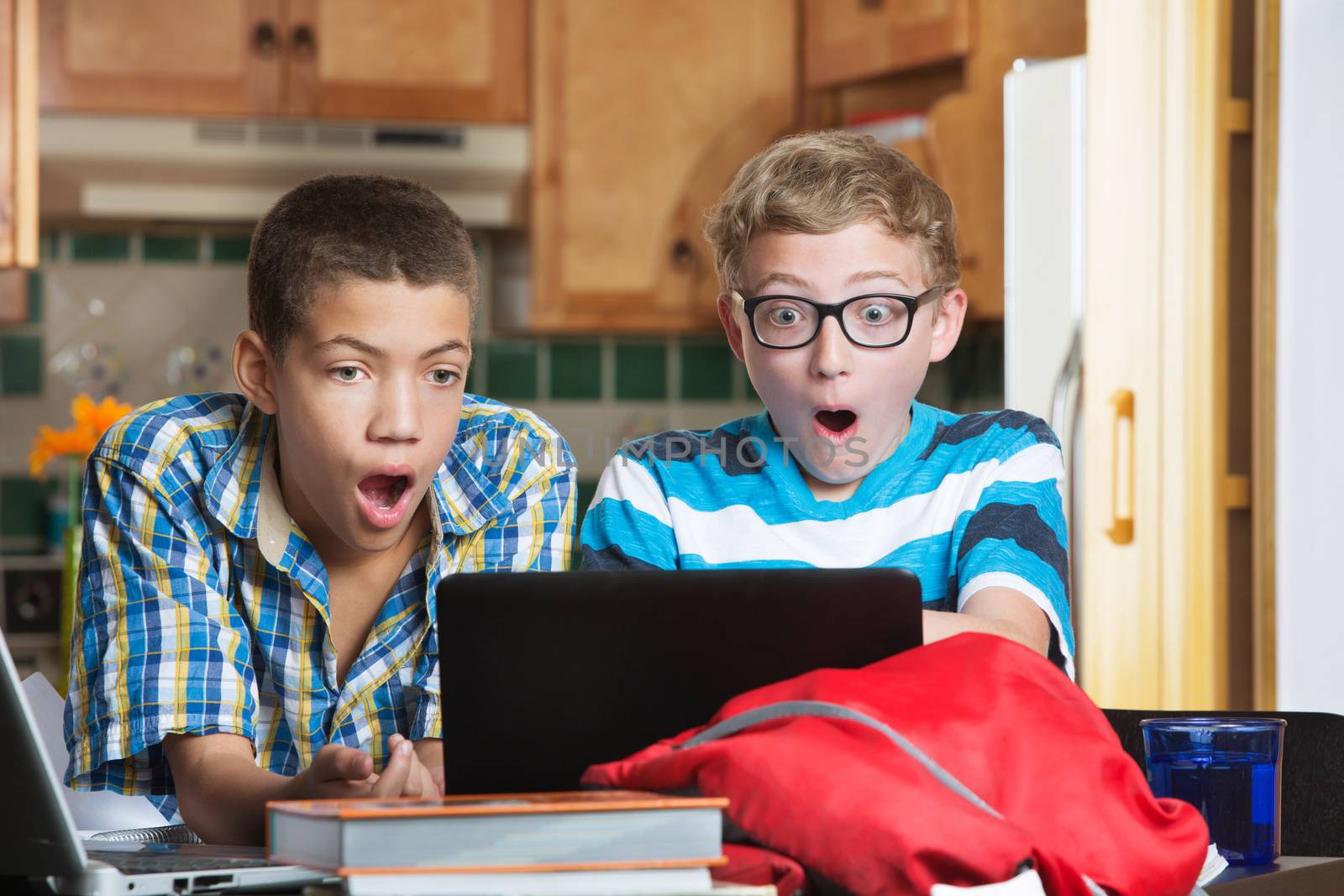Shocked teen males looking at laptop computer at home