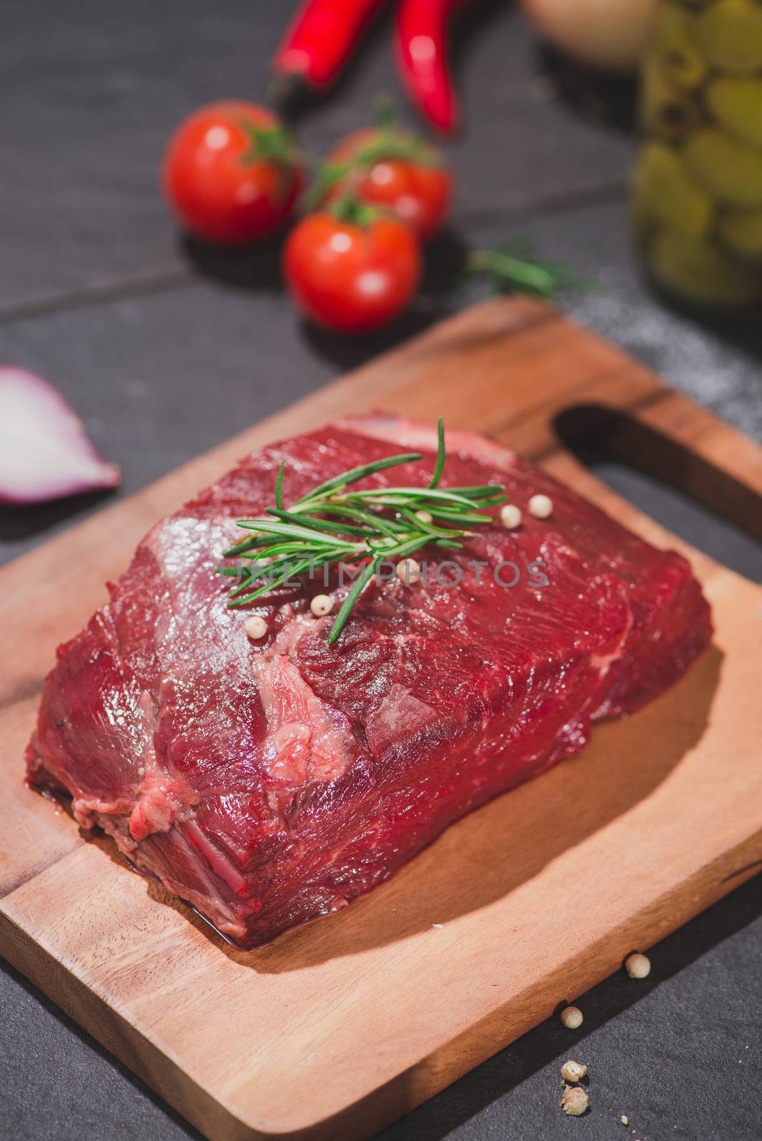 Raw beef on a cutting board  with spices and ingredients for cooking.