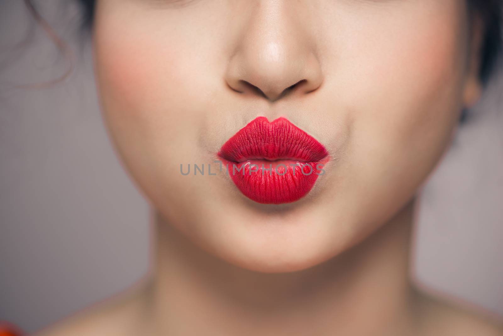 Woman's lips blowing a kiss with bright red lipstick by makidotvn