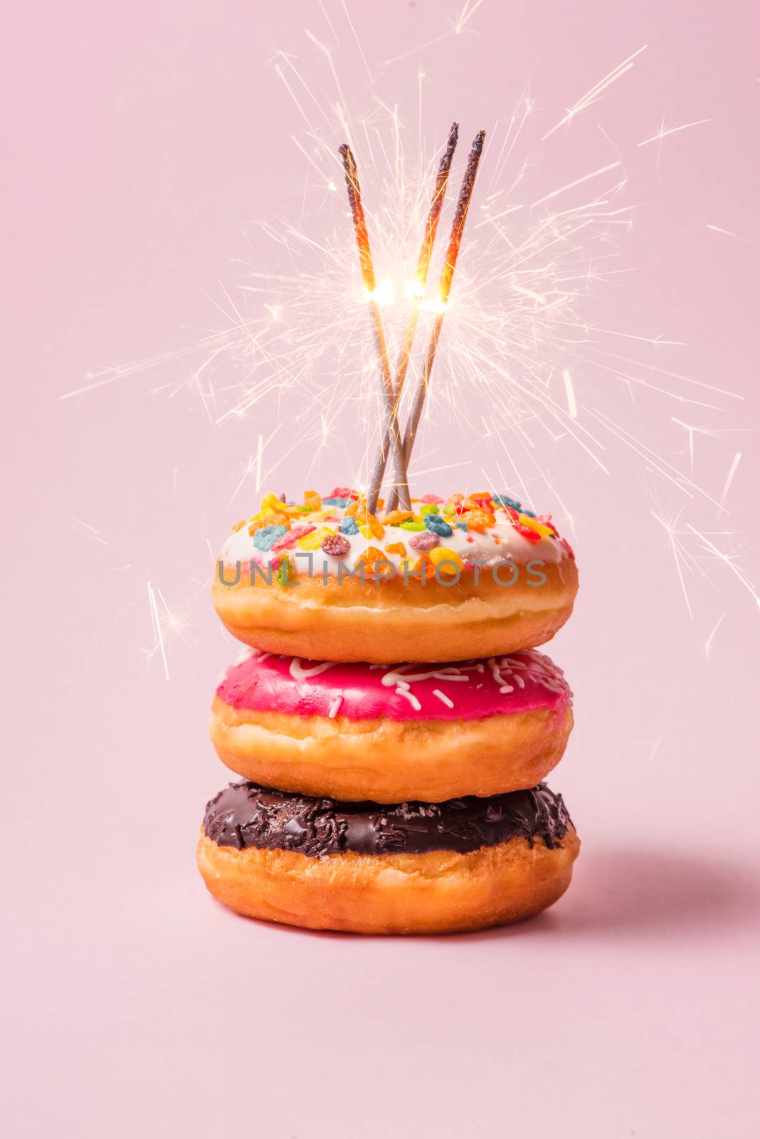 Delicious donuts for birthday on pastel pink background.