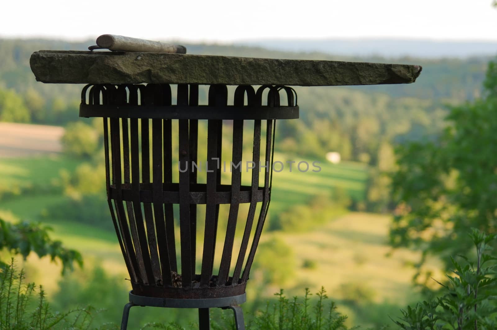 a empty portable BBQ grill in front of a fresh green summer landscape