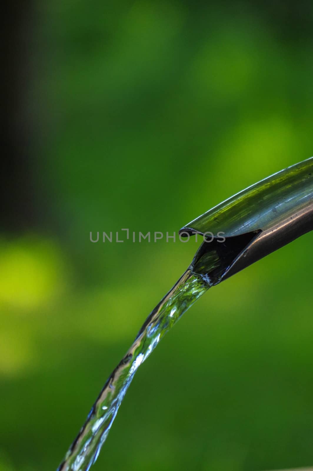 Close up of running water from a tap on green background