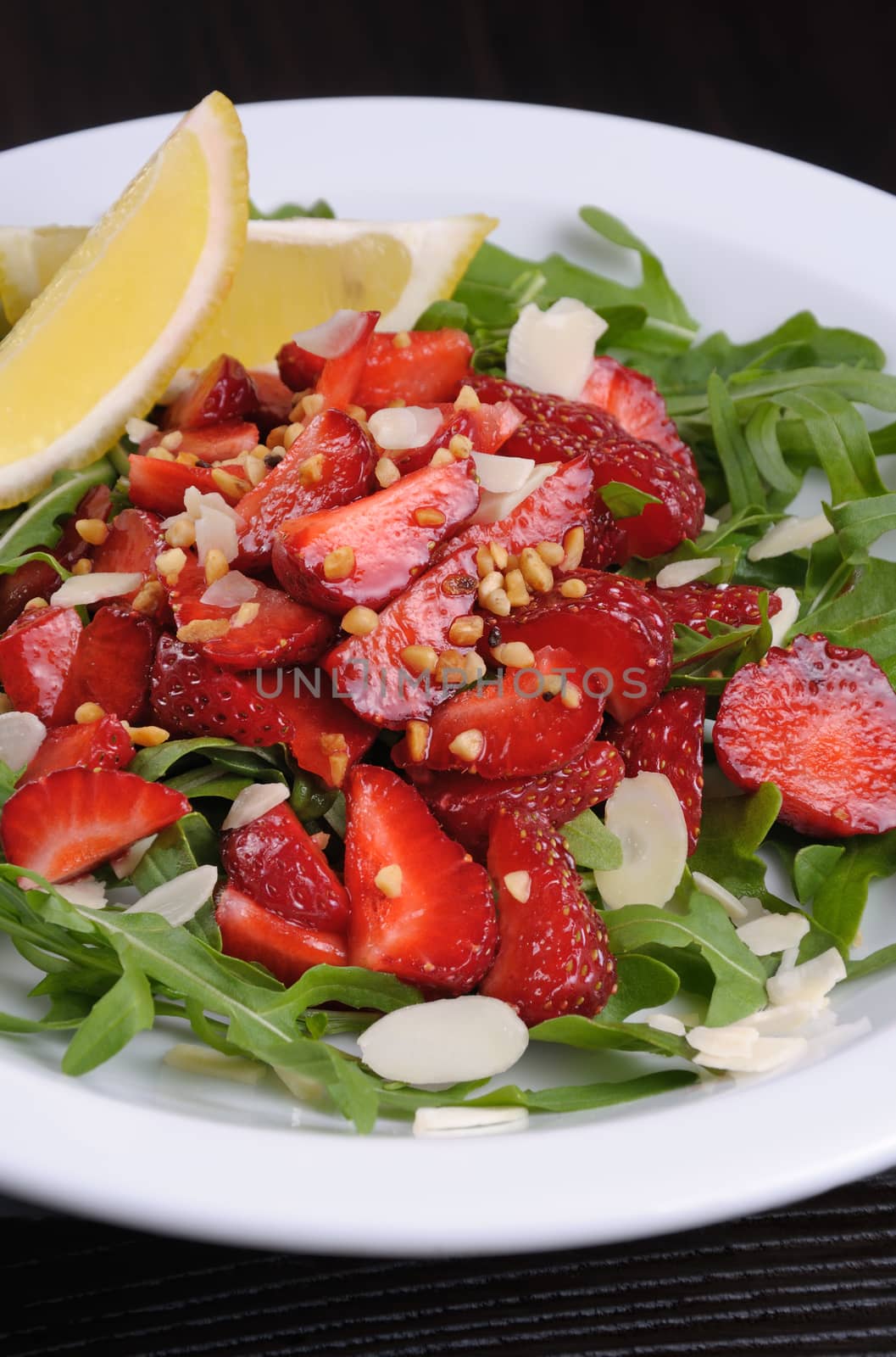 Salad of arugula and strawberries with crushed peanuts, almonds