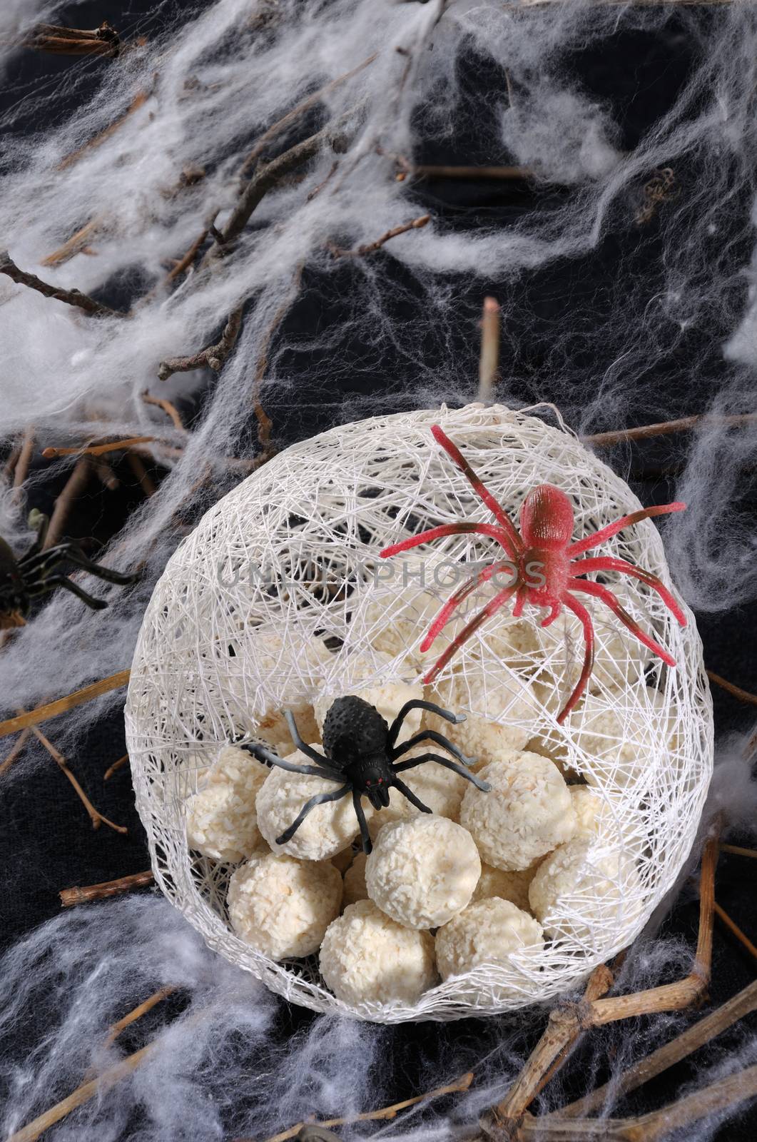 candy waffle balls in the form of spider eggs in a cocoon with a spider on the table for Halloween