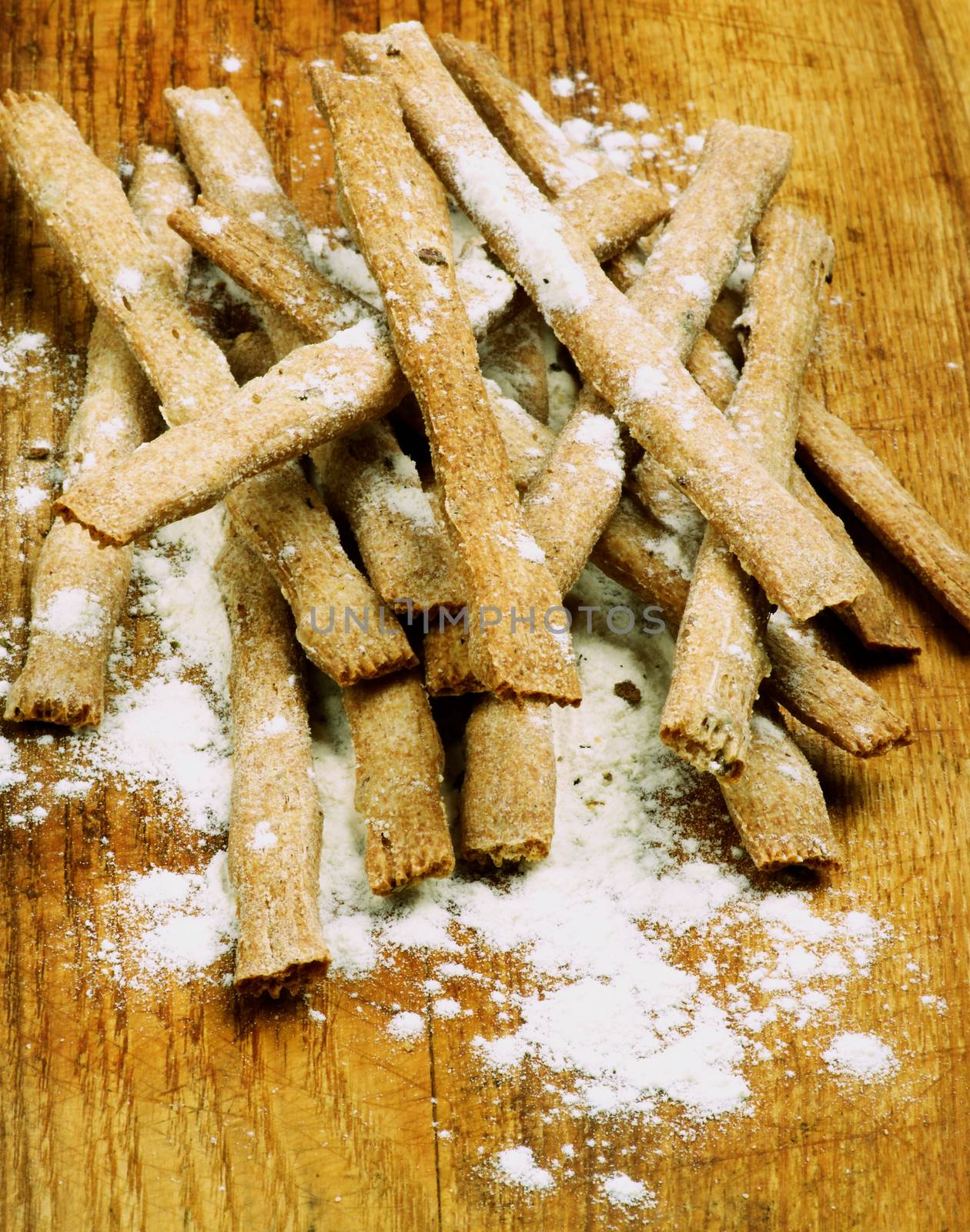 Stack of Freshly Baked Whole Wheat Bread Sticks with Dough closeup on Wooden Cutting Board