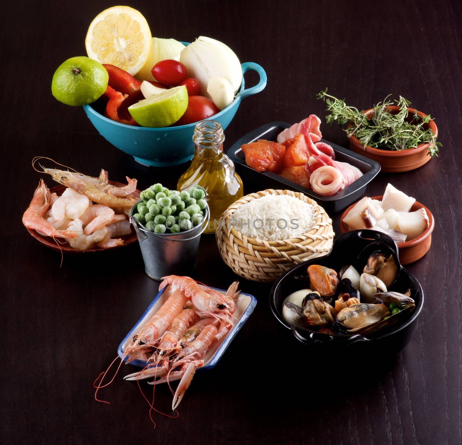 Raw Ingredients of Spanish Traditional Paella with Various Seafood, Mussels, Vegetables, Rice, Green Pea and Olive Oil closeup on Dark Wooden background