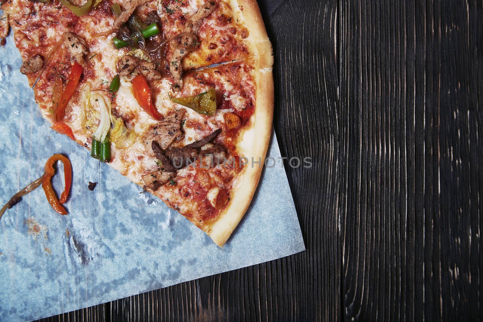 Part of homemade pizza on a wooden table