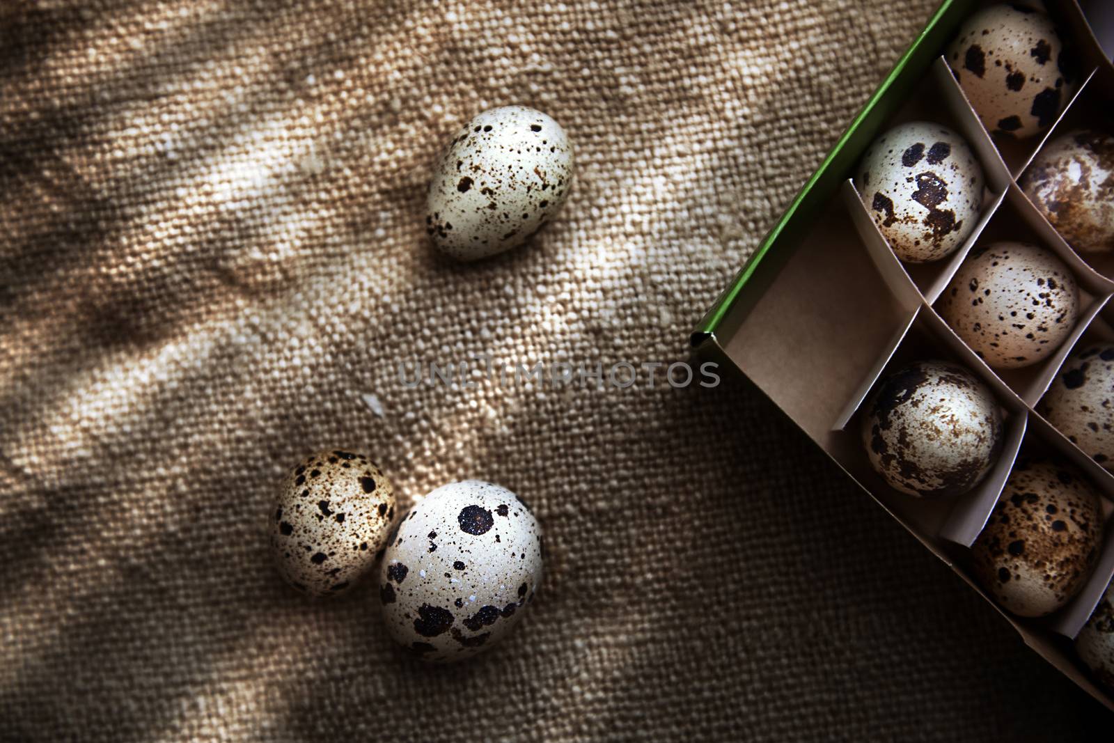 Quail eggs in carton box on a sackcloth. View from above
