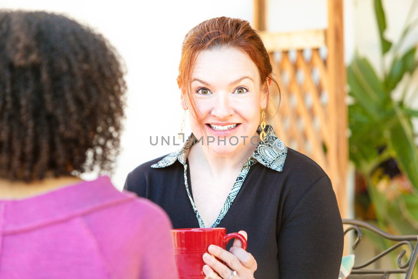 Caucasian woman with joyful expression seated with friend in cafe