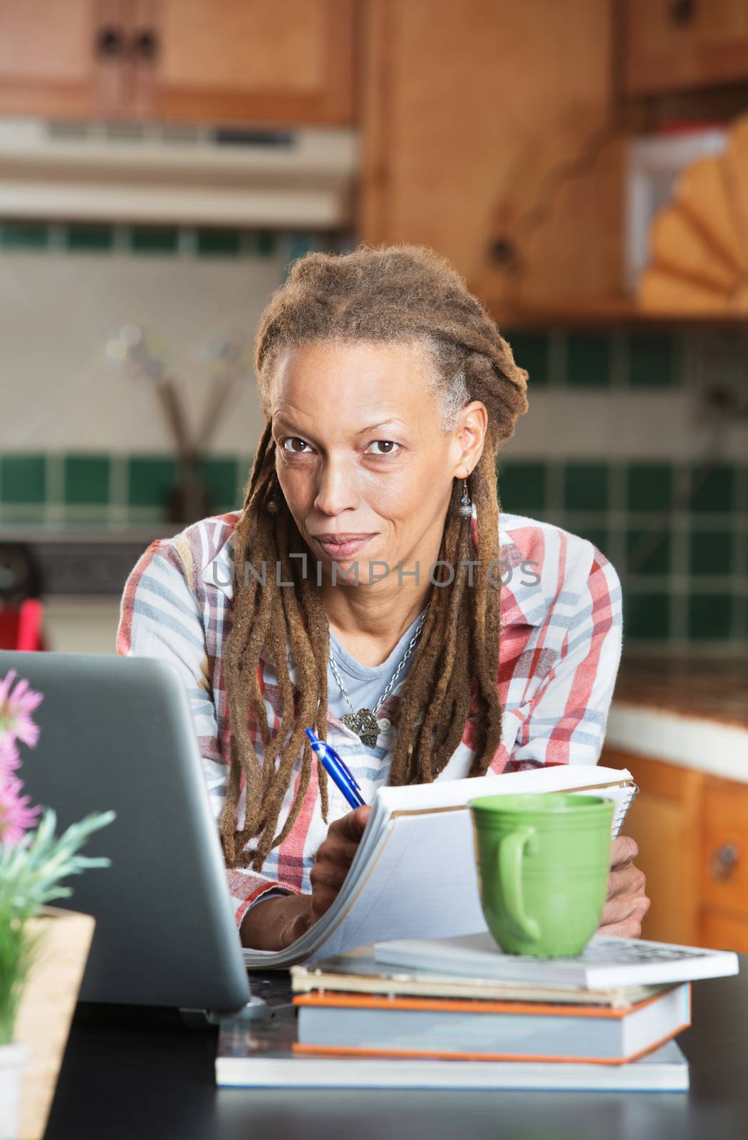 Beautiful grinning mature adult student with books and laptop computer indoors