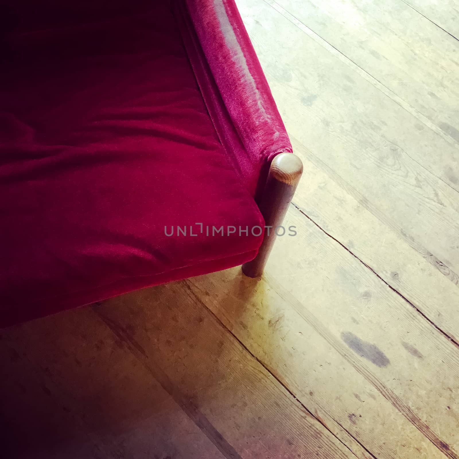 Vintage red velvet armchair on wooden floor. Retry style furniture.