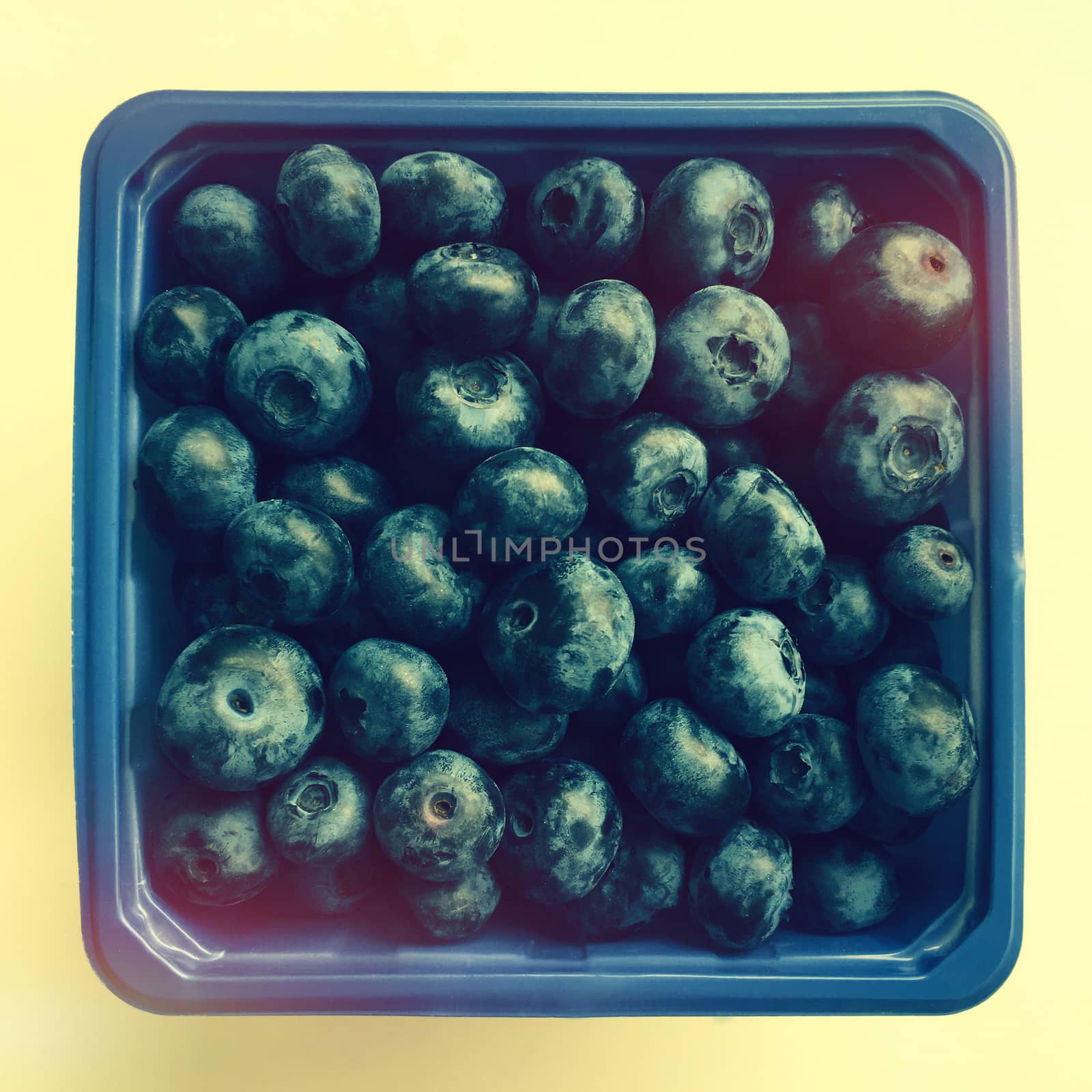 Box of ripe blueberries in retro light.