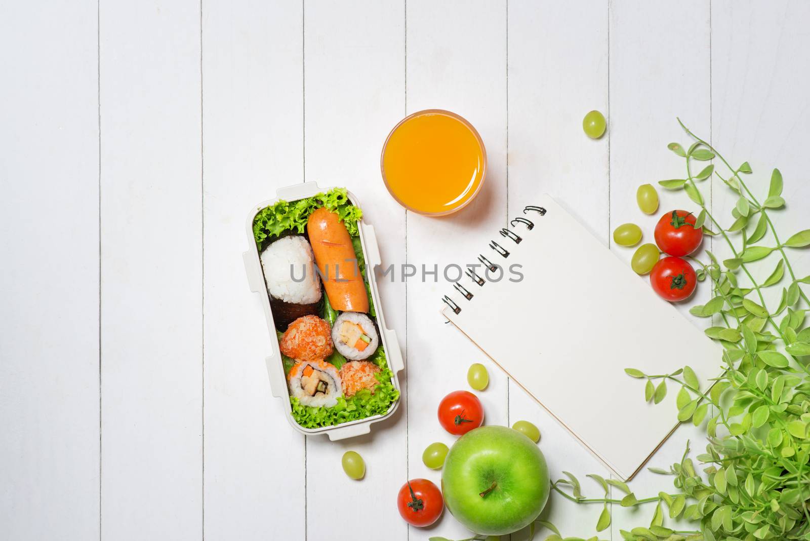 Bento box with different food, fresh veggies and fruits. Notebook with copyspace.