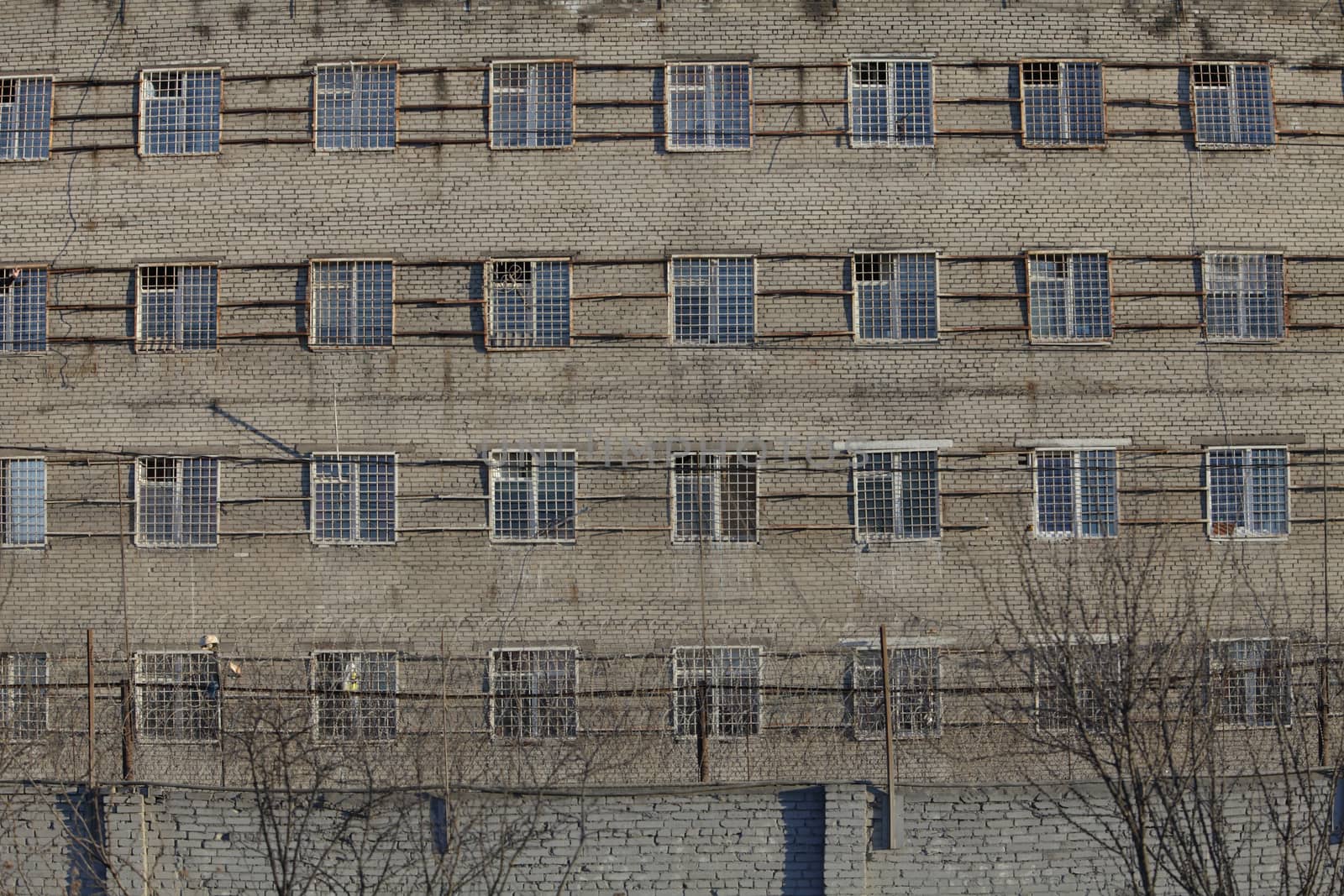 Wall of  prison building with barred windows