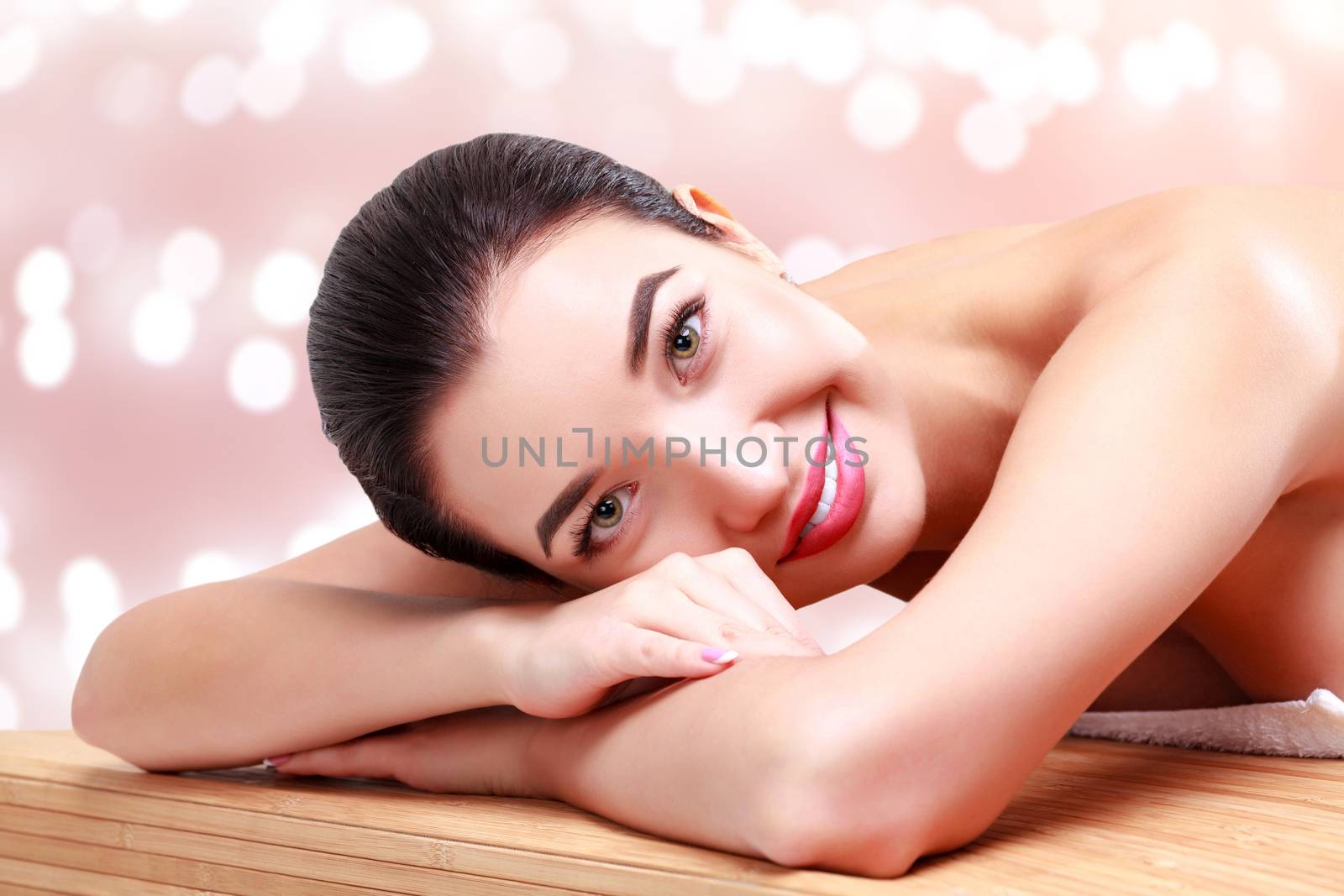 Young beautiful woman relaxing at spa salon. Abstract background with blurred lights