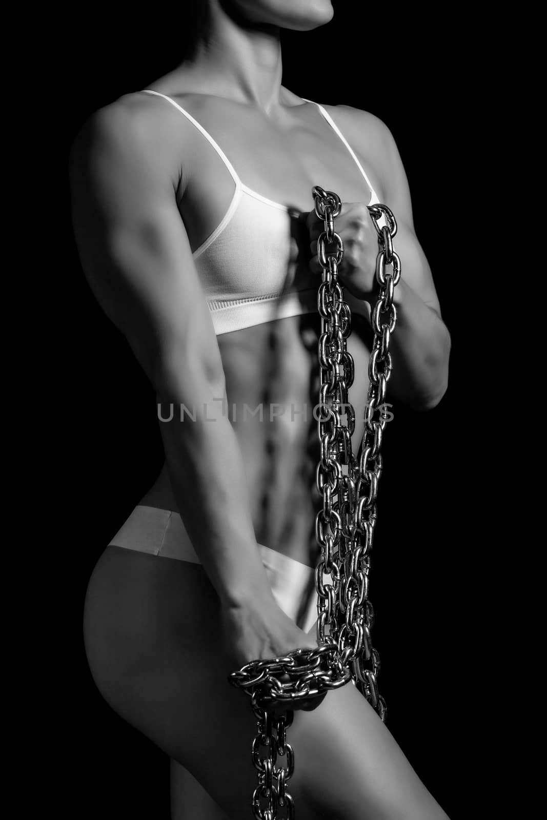 Strong woman with a thick iron chain on black background